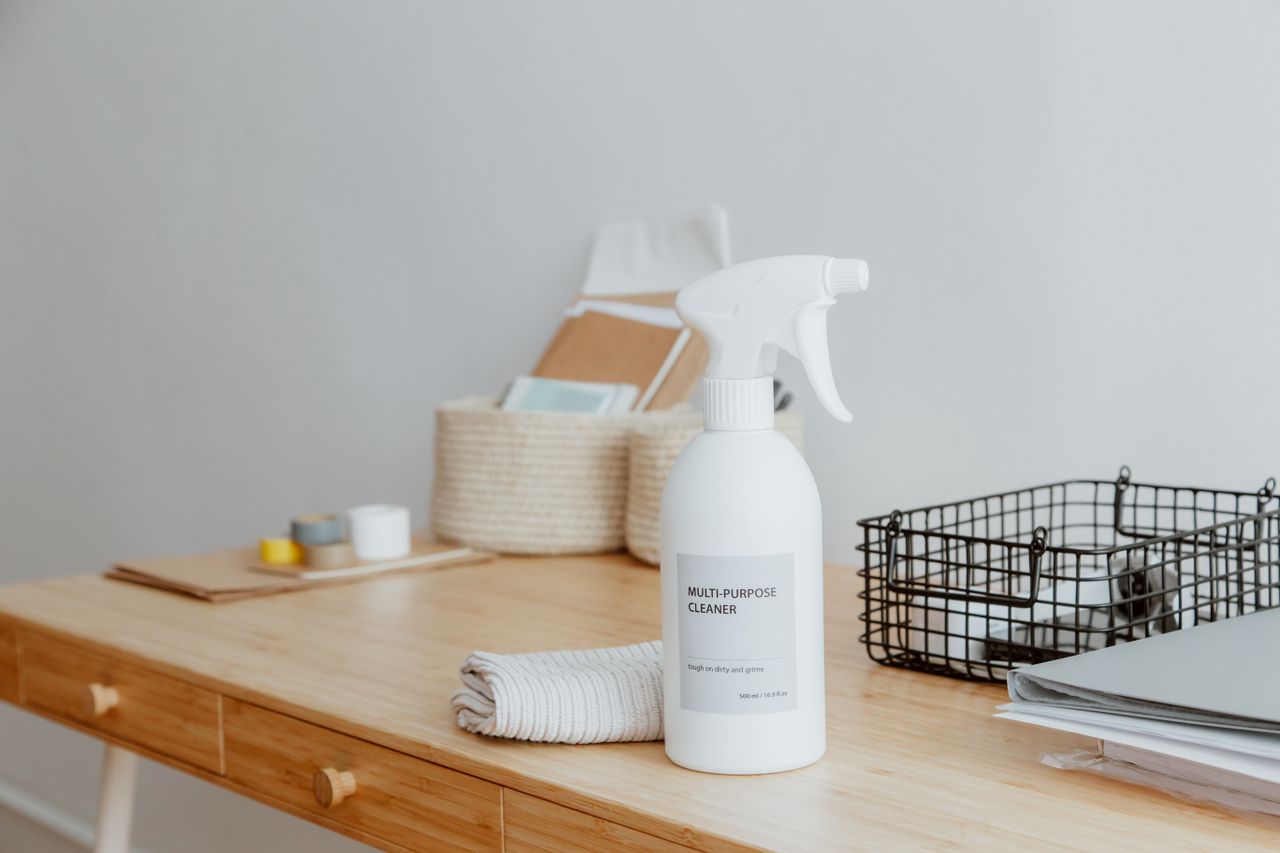 Minimalist desk centered on a multipurpose cleaner, office supplies, and storage solutions.